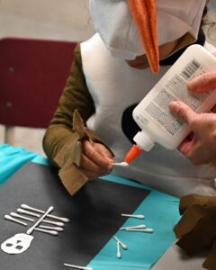 A student makes Halloween art while dressed as Olaf.