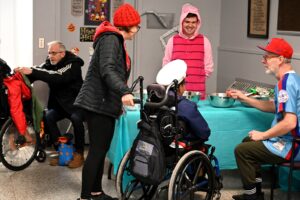 A wheelchair-using student dressed as a captain, surrounded by a baseball player and Piglet (Winnie-the-pooh).