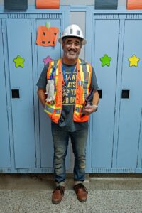 Rick Patricio smiles, dressed as a construction worker