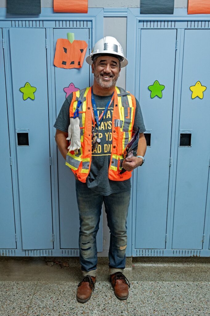 Rick Patricio smiles at the camera, dressed as a construction worker. // Rick Patricio sourit à la caméra, déguisé en travailleur de la construction.