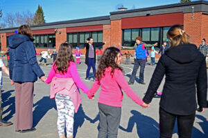 Onslow students hold hands in a circle while teachers lead an Irish jig on the inside of the circle
