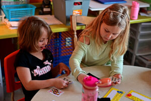 two grade 1 girls playing a math game involving playing cards
