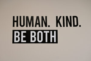 Message on the wall that says "Human. Kind. Be Both."