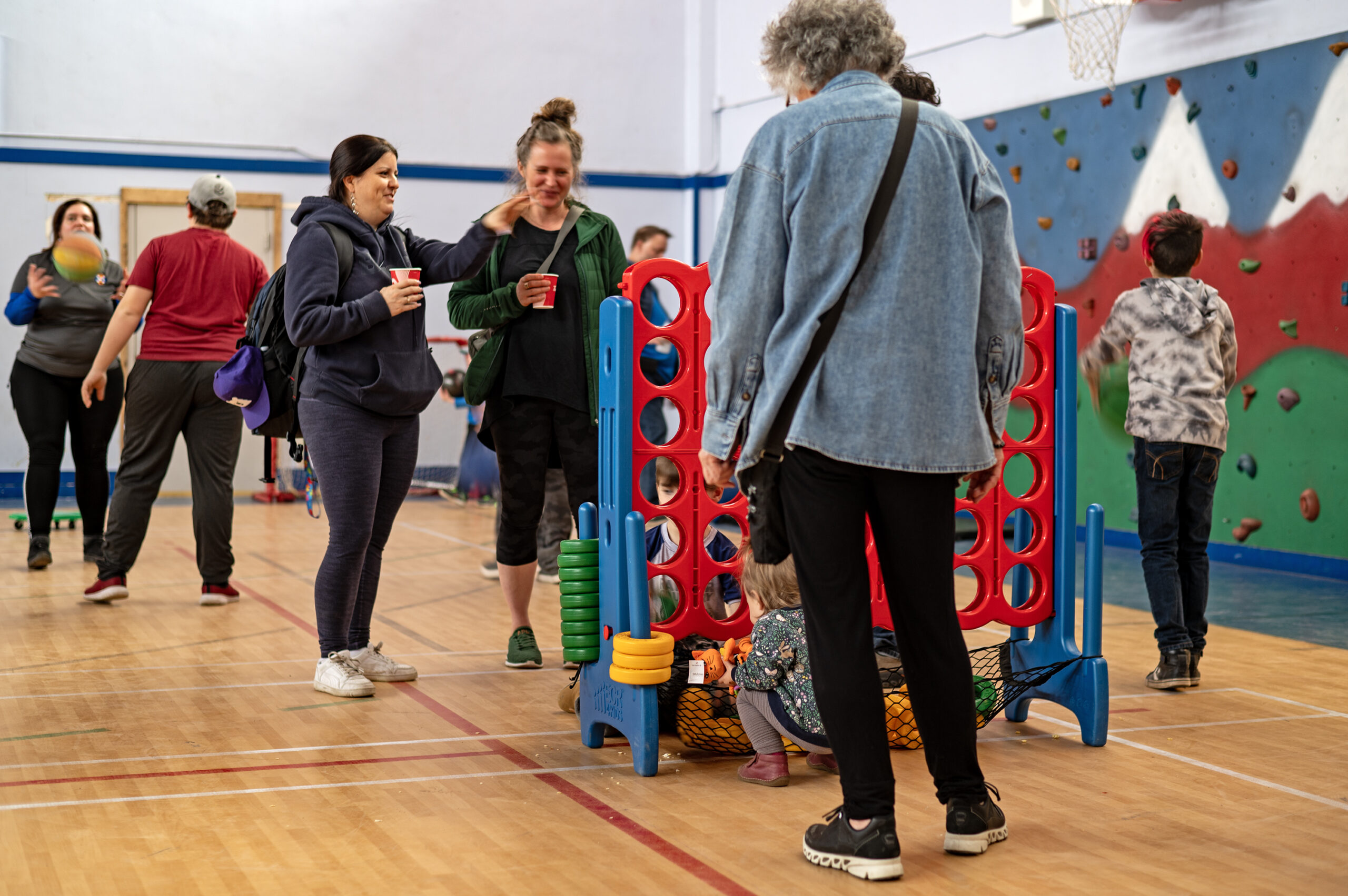A baby and a small child play with a giant connect four game