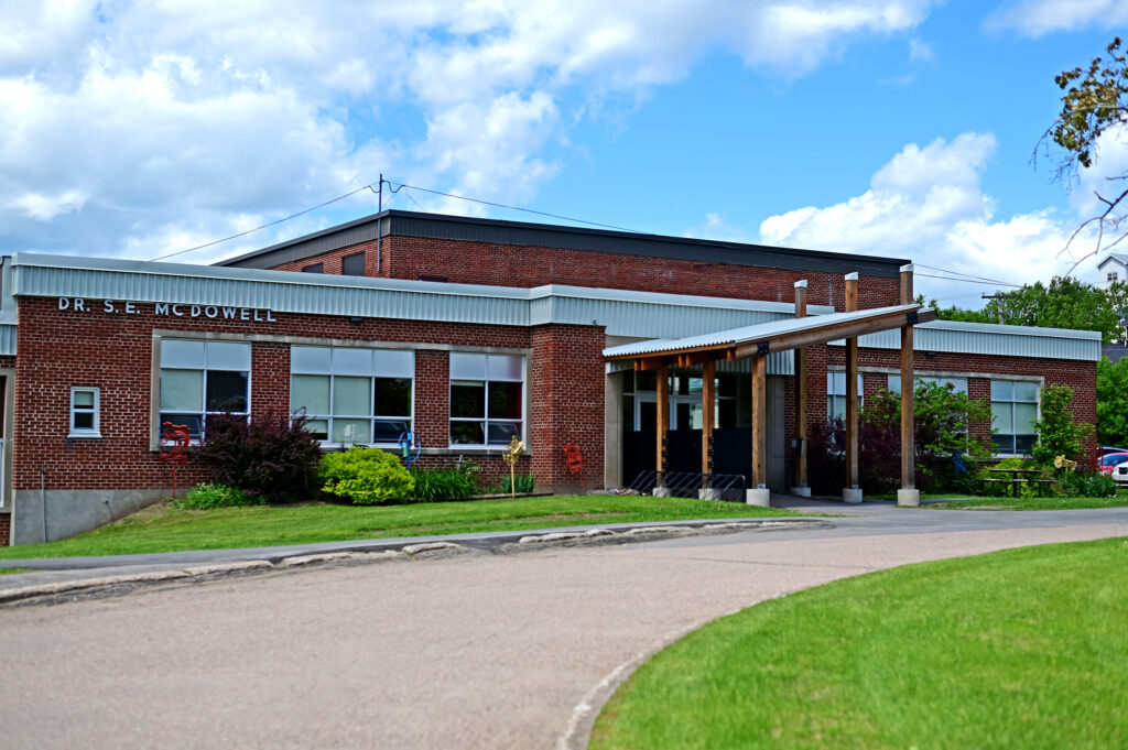 Extérieur de l'école, un bâtiment en brique rouge avec de l'herbe verte et un ciel bleu