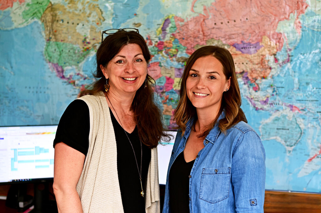 Polly Green and Trisha Willcott posing in front of a map in Polly's office